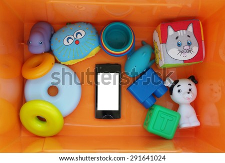Black smartphone with white screen in a box with toys