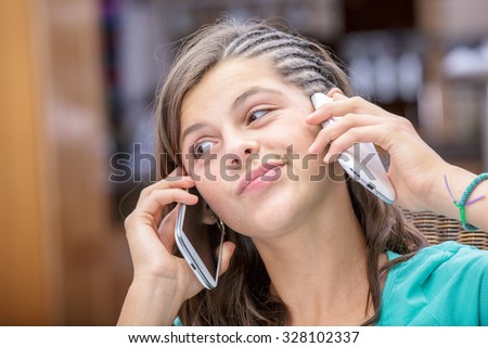 concept portrait of addict young girl having an animated conversation with a phone in each hand