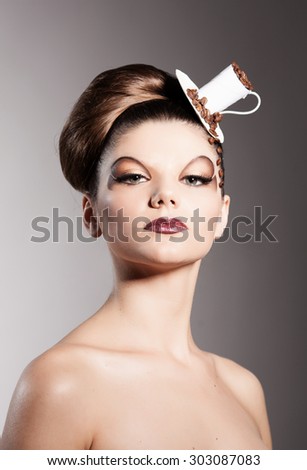 Beautiful girl in a hat stylized cup of coffee with coffee beans on the face looking up