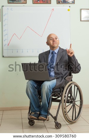 Happy businessman in a wheelchair on the background of the chart. Successful disabled person. Wheelchair user works.