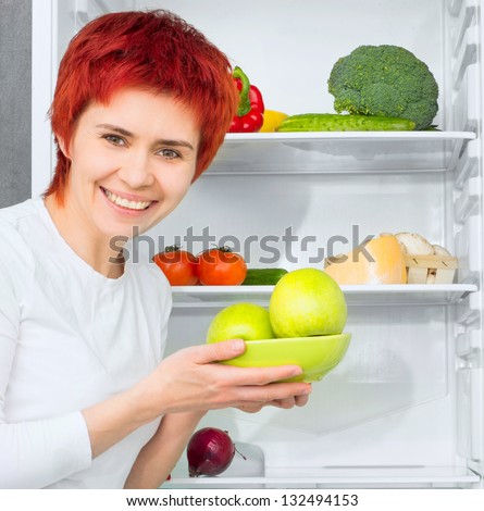 young woman with apples against the refrigerator with food