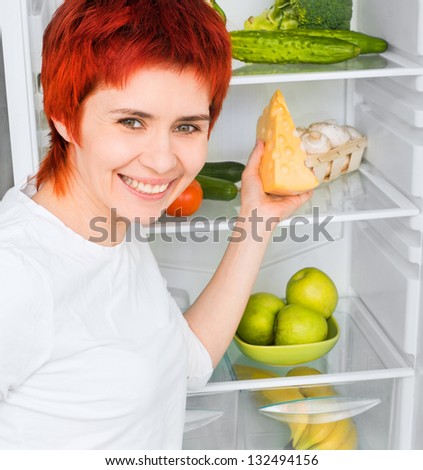 young woman with apples against the refrigerator with food