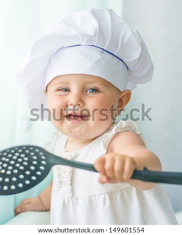 smiling baby in chef\'s hat with kitchen tool