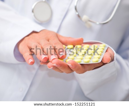 doctor holding a pack of yellow pills