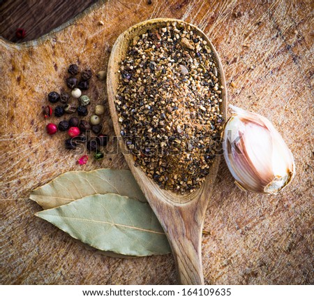 spices in a wooden spoon with laurel leaves on a cutting board