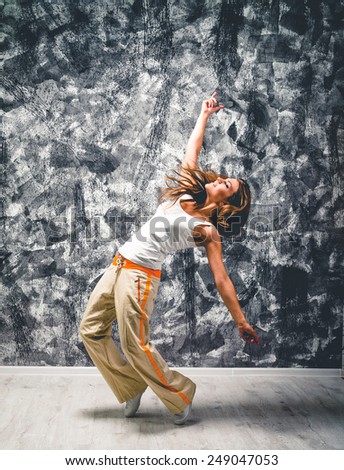 Young woman dancer jumping. On grunge wall background