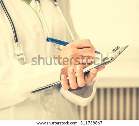 doctor standing and making notes in a notebook