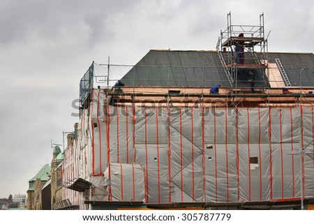 HAMBURG, GERMANY - SEPTEMBER 20, 2011: View of building reconstruction process. Workers are covering roof of the building with copper plates.