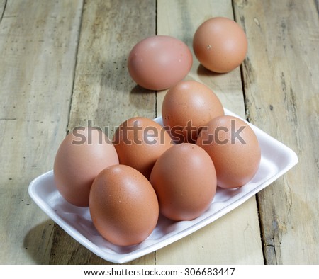 The eggs in foam box on the wood background.