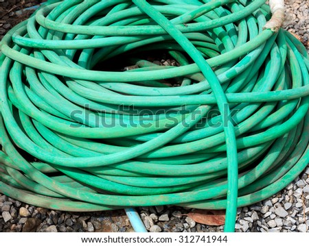 Green water hose on the rock background.