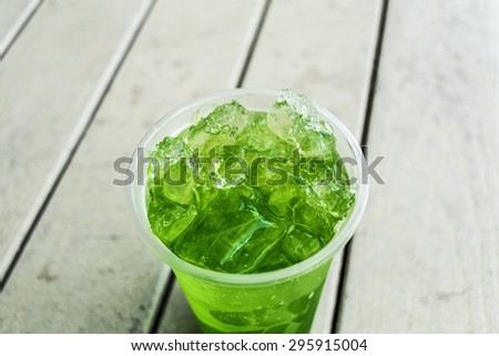 An image of green juice in plastic cup full filled by ice
