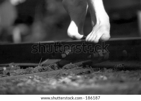 Close-up of bare feet walking on railroad tracks