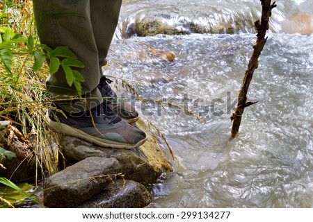 Close up of male hiking boots on hiker  walking crossing river creek