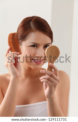 Young woman holding mirror and wooden comb