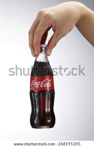 Kuala Lumpur,Malaysia 9th April 2015,Photo of a hand holding glass bottle of Coca Cola - Refreshing. Wet with water ice droplets