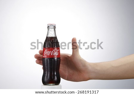 Kuala Lumpur,Malaysia 9th April 2015,Photo of a hand reaching glass bottle of Coca Cola - Refreshing. Wet with water ice droplets