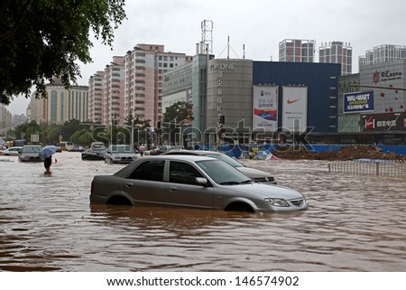 KUNMING - JULY 19: Unidentified people and vehicles caught in the flooded streets, Kunming China July 19, 2013