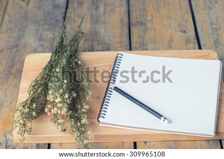 vintage notepad with dry flowers on wood table, selective focus at white paper