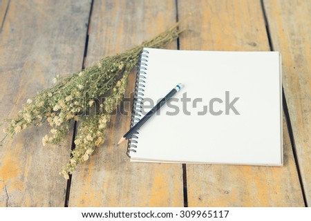 vintage notepad with dry flowers on wood table, selective focus at white paper
