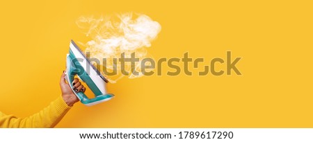 modern iron with steam in hand over yellow background, panoramic mock-up image Stock foto © 