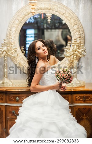Beauty adult bride in white wedding dress indoor. Mirror behind