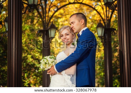 Smiling bride and groom near street lights in park
