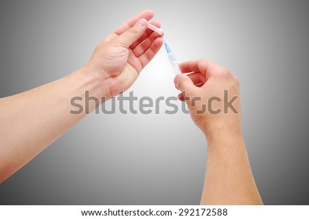 Hand of a doctor with a syringe . People remove the protective cap from the needle to the syringe prior to vaccination .