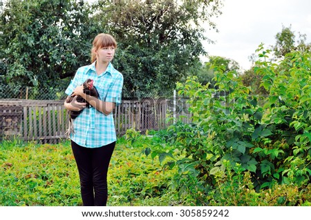 The farmer with chicken in hands against a kitchen garden