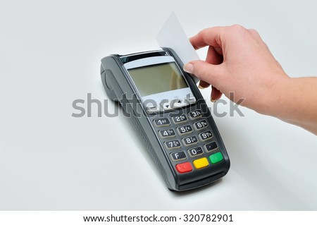 The girl holds in hand a credit card in front of the terminal on white background. A white credit card without image. Payment by a credit card in the terminal