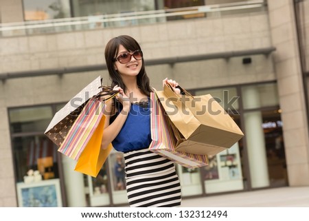 Fashion lady of Asian holding shopping bags in modern city.