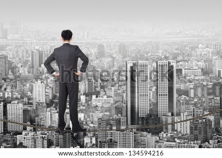 Chinese business man stand on rope. Photo manipulation  about risk, adventure, future or dream etc.
