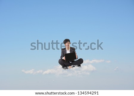Asian businessman sit on cloud and show you blank pad screen in blue sky. Concept about business, cloud, technology, pad etc. Blank pad screen on hand and copyspace on sky.