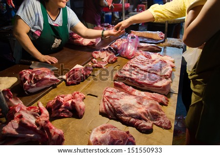 TAIPEI, TAIWAN - October 7 : A buyer buy the pork with the butcher in the dark and traditional marketplace on October 7, 2012 in Taipei, Taiwan, Asia.