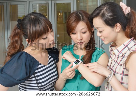 Asian woman using wearable watch and showing to her friends.