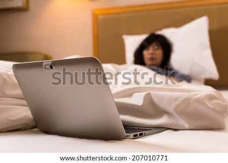 Asian woman falling asleep while the laptop on bed.