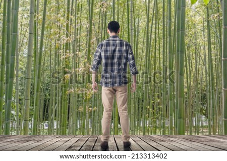 Man standing and looking into the bamboo forest, concept of relax, freedom, zen etc.