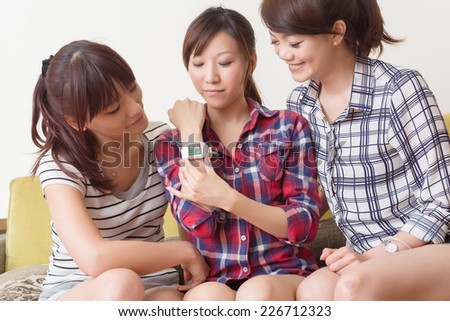 Asian woman using wearable watch and showing to her friends.