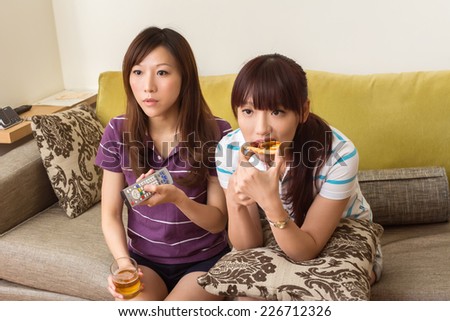 Group of Asian women chat and watch tv in the living room.