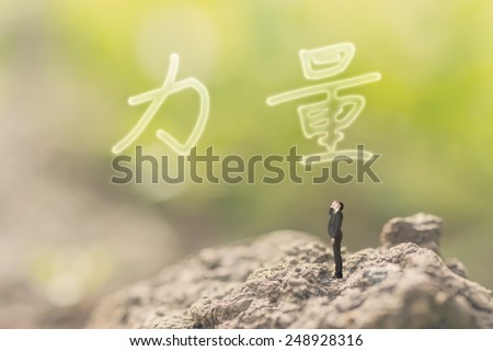 one person stand in the outdoor and looking up the Chinese text(mean power) on nature background, concept of power, strength, force.