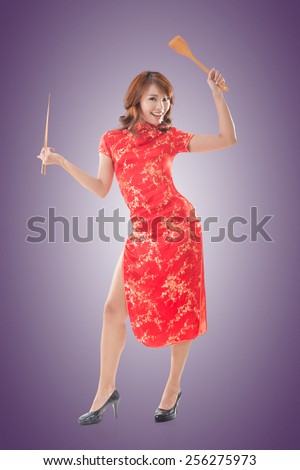 Smiling Chinese woman dress traditional cheongsam standing and holding chopsticks at New Year, full length portrait isolated.