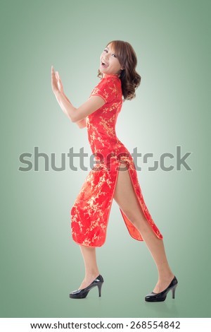 Chinese woman dress traditional cheongsam and push something at New Year, full length portrait isolated.