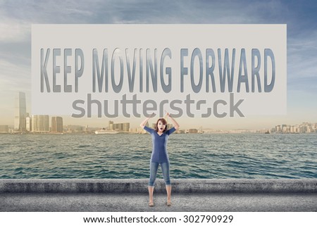 Keep moving forward, words on blank board hold by a young girl in the outdoor.