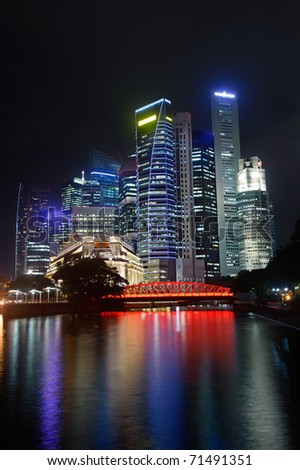 Colorful city night with skyscrapers near river in Singapore, Asia.