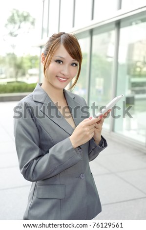 Young business manager holding pad and smiling, half length closeup portrait outside of modern buildings.