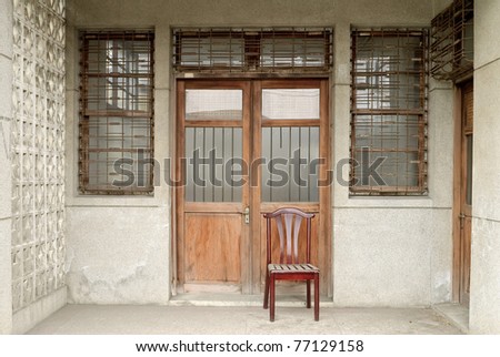 Nostalgic Chinese old building exterior with door and wall in grungy style and single chair in Taiwan, Asia.