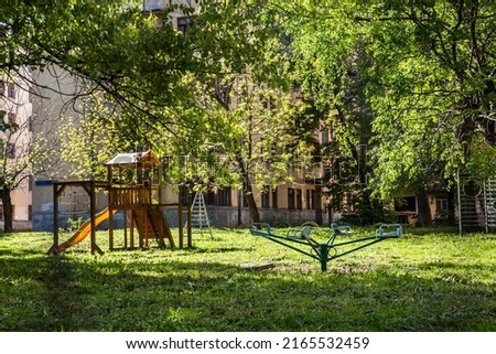 An empty abandoned playground in the courtyard of a dilapidated house for renovation. Attraction, swing. Summer sunny day. The concept of childhood and outdoor games. Moscow, Russia Photo stock © 