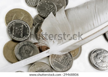 foreign currencies coins and a feather macro isolated on white background