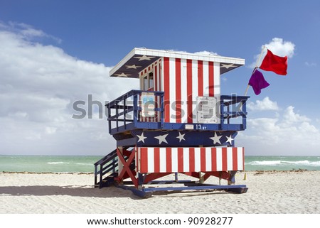 Summer scene with a lifeguard house in Miami Beach, Florida in the colors of the American flag with blue sky and ocean in the background.