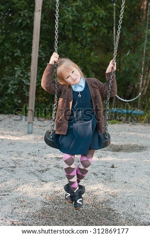 Girl in school uniform on a swing