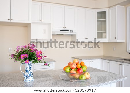 New house closing day. Empty kitchen. Fruits and flower on granite counter top. White cabinet.